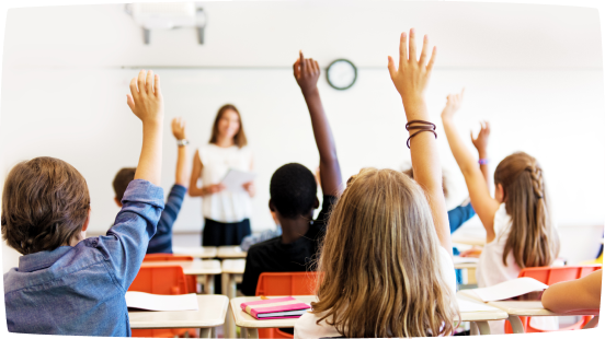 Mehrere Schülerinnen und Schüler melden sich im Unterricht, während eine Lehrkraft vorne im Klassenzimmer steht