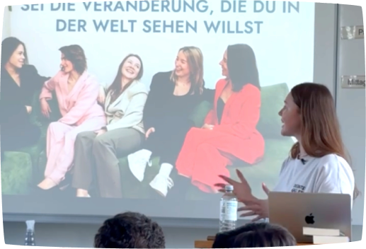 Lehrkraft erläutert einer Klasse Inhalte, die auf der Leinwand präsentiert werden.