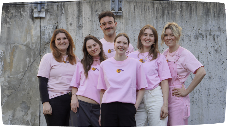 Fünf Frauen und ein Mann tragen gemeinsam rosa LifeTeachUs-T-Shirts und posieren für ein Gruppenfoto.